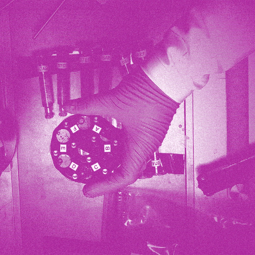 Halftone photograph of a gloved hand holding a round sample disc, in duotone scanlines